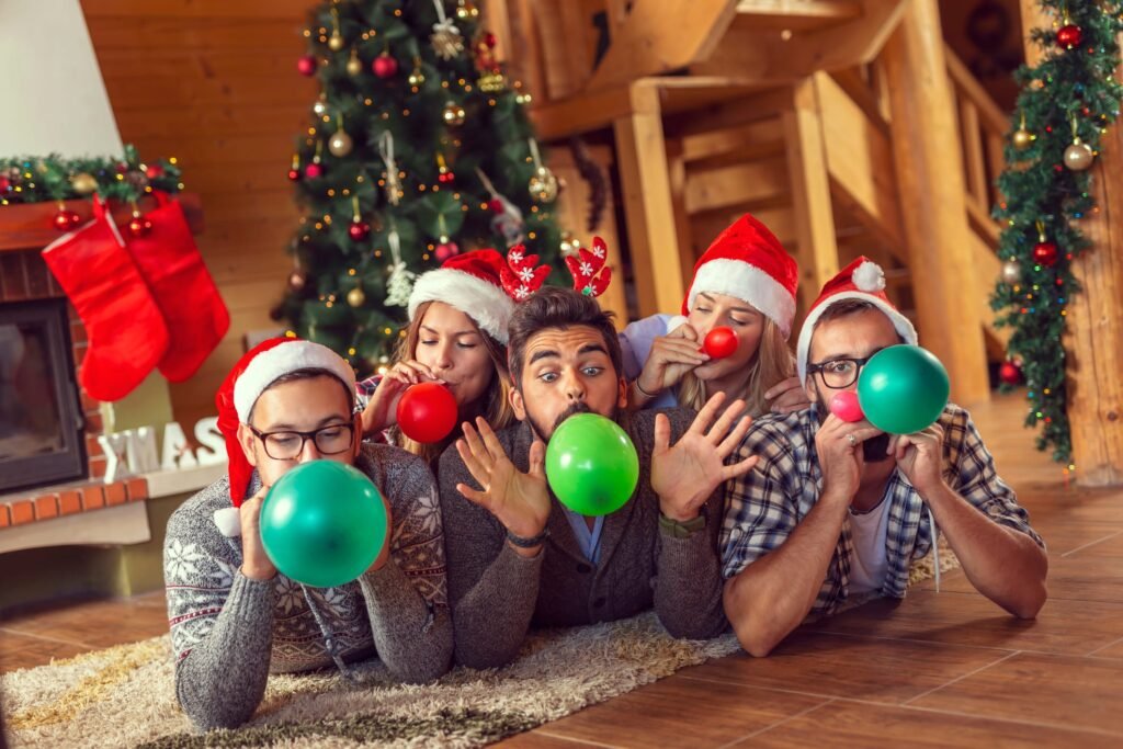 Group of friends lying next to a fireplace and Christmas tree, having fun on Christmas morning, blowing colorful balloons and decorating the house